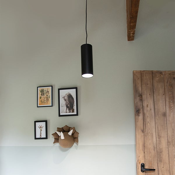 Schwarze Hängelampe über Bildern und einer Holztür