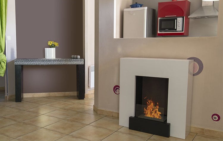 Wohnraum mit modernem Ethanol-Kamin als zentrales Element, Fliesenboden und angrenzender kleiner Küchennische mit Einbaugeräten.