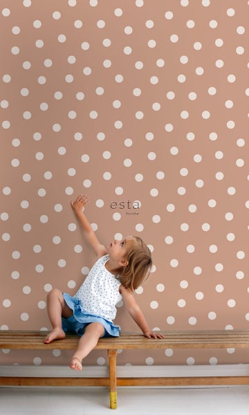 Mädchen sitzt vor einer Wand mit Punktmuster der Marke Esta Home