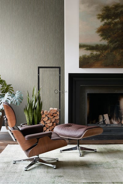 Wohnzimmer mit Sessel, Fußhocker, Kamin und Zimmerpflanzen