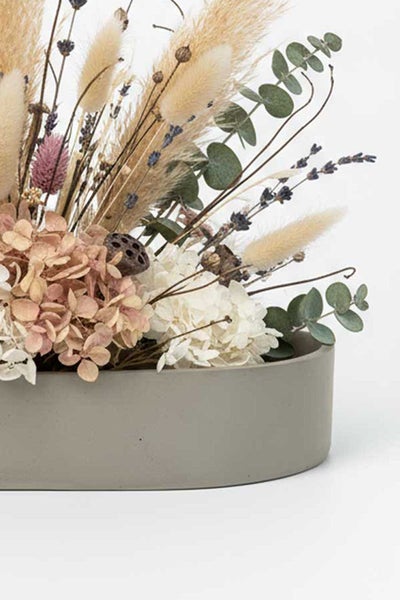 Trockenblumenarrangement in einer grauen Betonschale mit Pampasgras, Eukalyptus, Hortensien und Lavendel.
