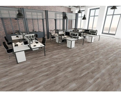 Modernes Großraumbüro mit grauem Bodenbelag in Holzoptik, weißen Schreibtischen und industriellen Elementen wie Ziegelwänden.