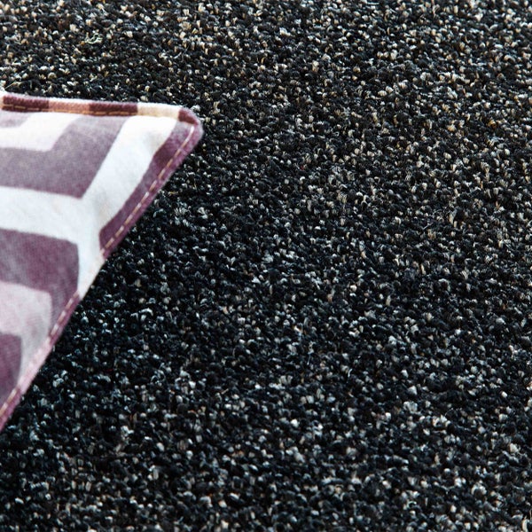 Teppichboden mit dichter Struktur und gemustertem Kissen in der Ecke.