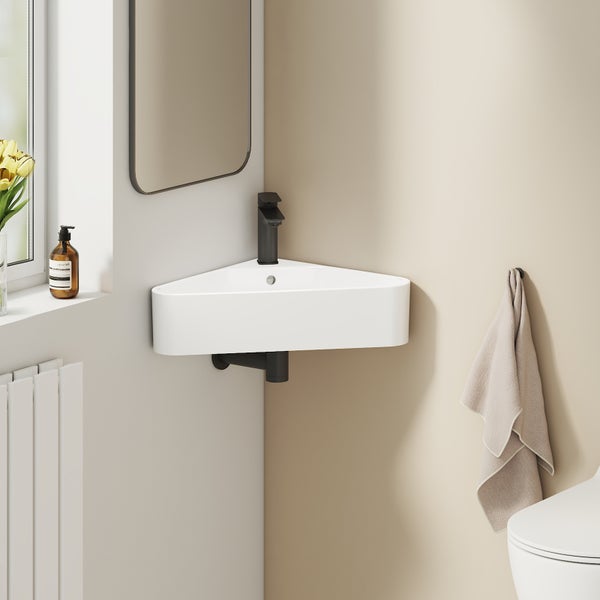 Modernes Eckwaschbecken aus Keramik mit schwarzer Armatur in einem hellen Badezimmer mit Spiegel und Handtuch.