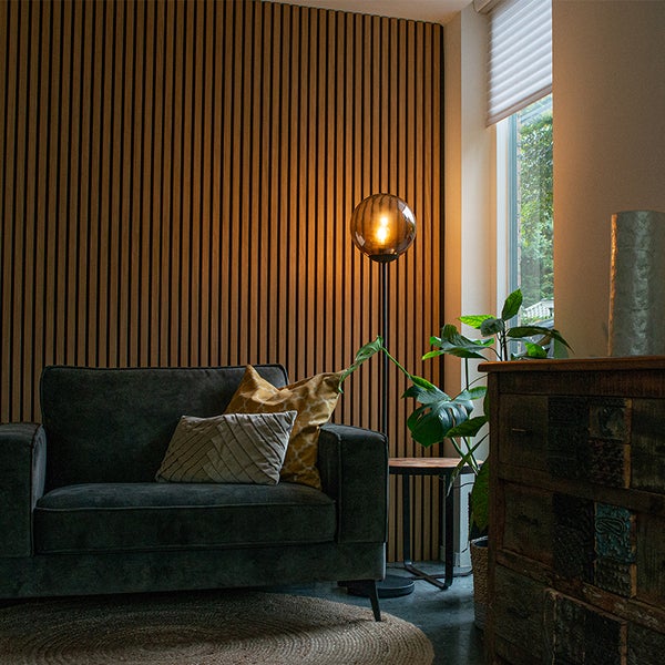 Wohnzimmer mit Holzpaneelwand, Sessel und Stehlampe