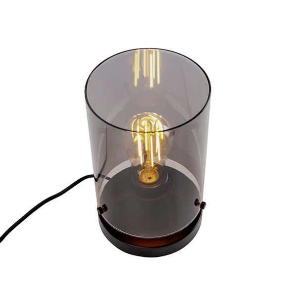 Tischleuchte mit zylindrischem Rauchglasschirm und sichtbarem Filament-Leuchtmittel auf schwarzem Sockel.