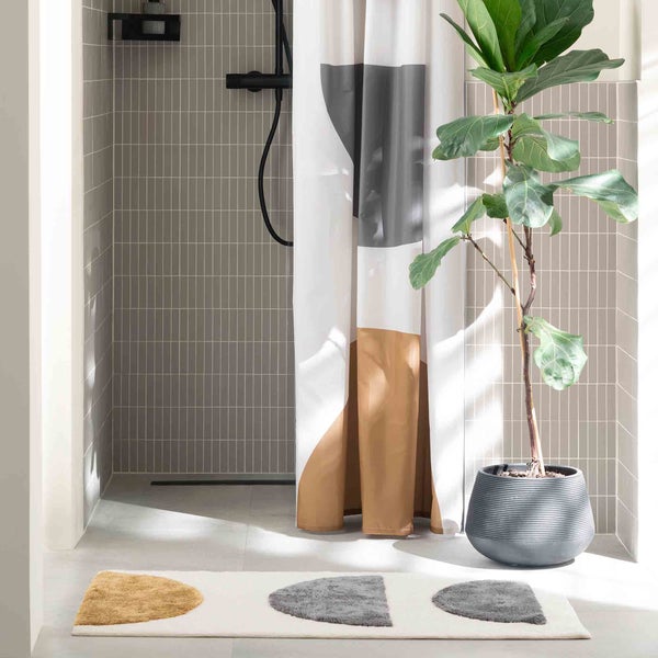 Modernes Badezimmer mit Dusche, Duschvorhang mit grafischem Muster, Zimmerpflanze im Topf und Badteppich mit Halbkreis Design
