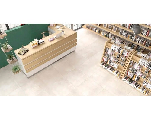 Moderne Raumgestaltung mit hellen Bodenfliesen in einem Buchladen mit Theke und Regalen aus Holz.