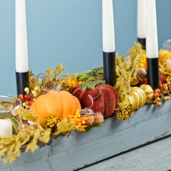 Dekoration mit Kürbissen, Kerzen und Herbstlaub in Holzkiste