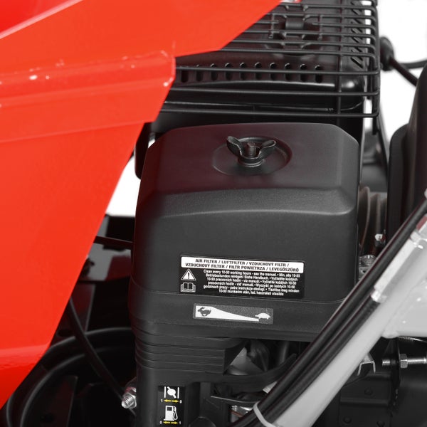 Luftfiltergehäuse eines Motors mit Flügelschraube und Hinweisschildern zur Wartung.