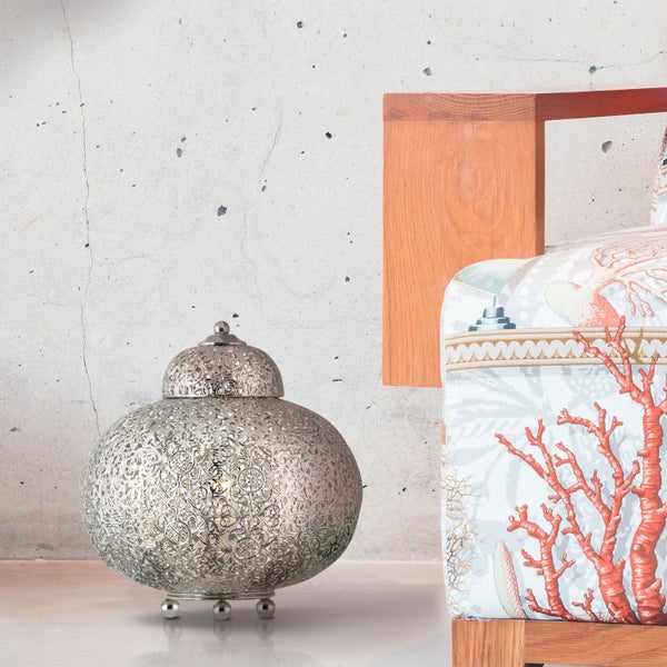 Dekorative Metalllaterne neben einem Bett mit Korallenmuster.