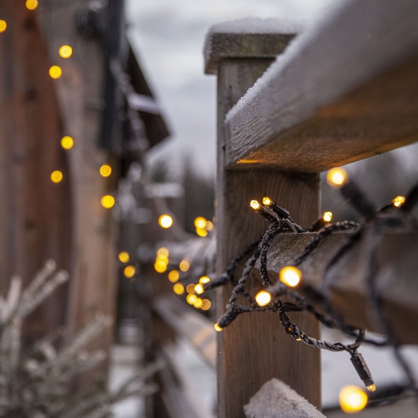 Holzzaun mit Lichterkette im Winter