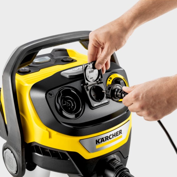 Eine Hand schließt die Steckdosenabdeckung an einem Karcher Mehrzwecksauger während die andere den Netzstecker hält.