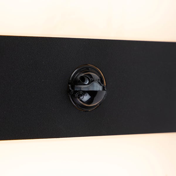 Detailaufnahme eines Bewegungssensors an einer schwarzen Wandleuchte.