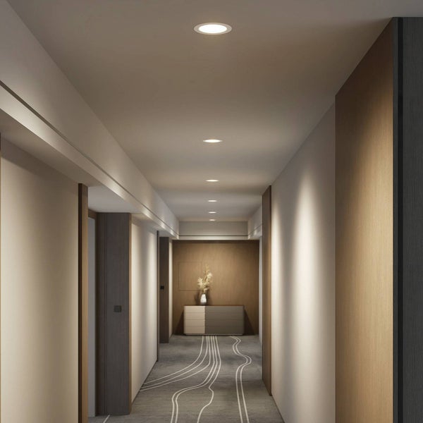 Moderner Flur mit runden LED-Einbaustrahlern an der Decke, Holzpaneelen an den Wänden und gemustertem Teppichboden.