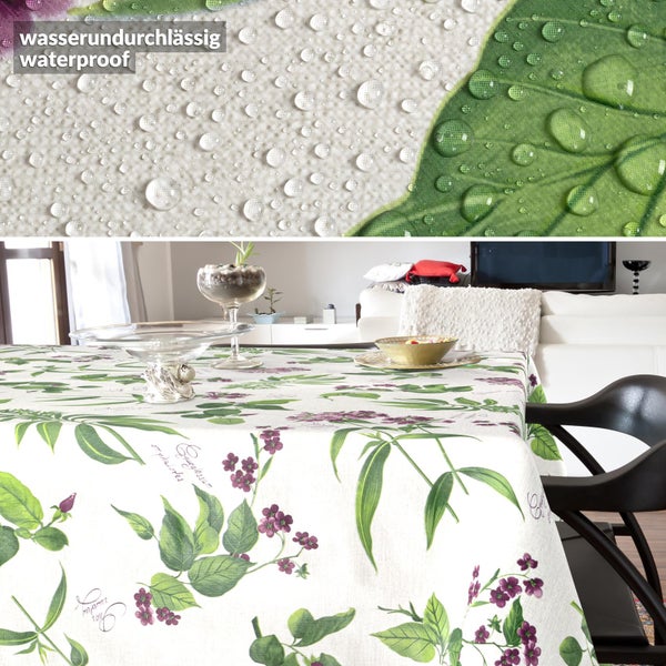 Wasserdichte Tischdecke mit botanischem Muster aus grünen Blättern und lila Blüten. Nahaufnahme zeigt wasserabweisende Oberfläche mit Wassertropfen.