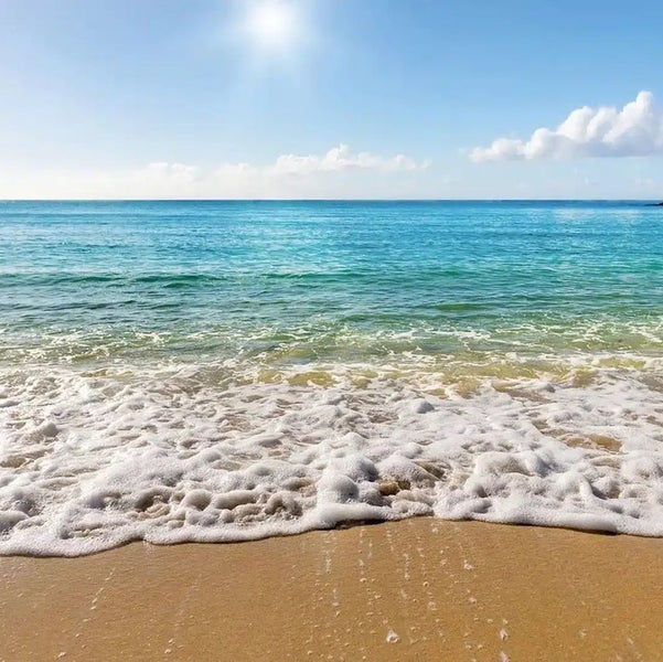 Fototapete mit Strandmotiv, Meer, Wellen am Ufer, Sand und sonnigem Himmel mit Wolken.