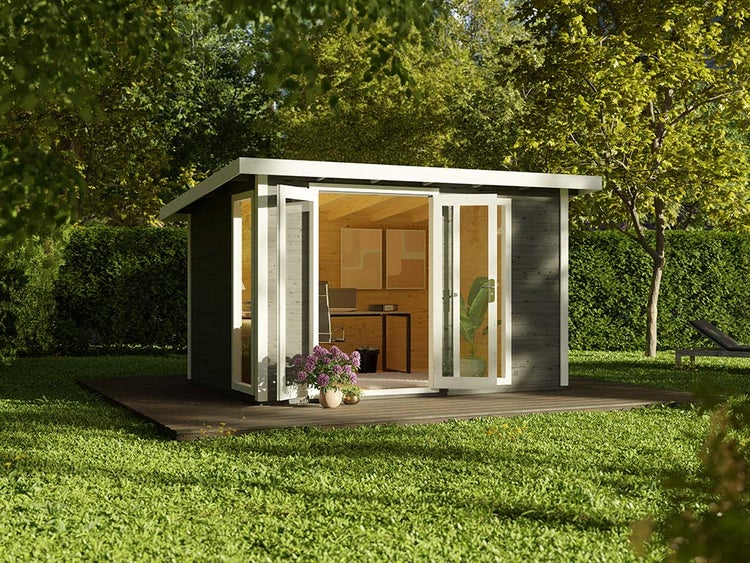 Modernes Gartenhaus aus Holz mit Flachdach, als helles Büro eingerichtet, mit Glasfront und Doppeltür auf einer Holzterrasse im grünen Garten.