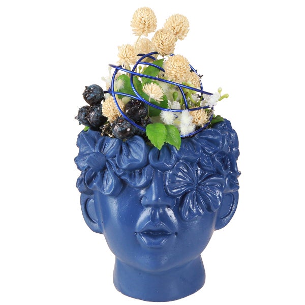Blauer Übertopf in Form eines Gesichts mit Blumen und Zierbeeren