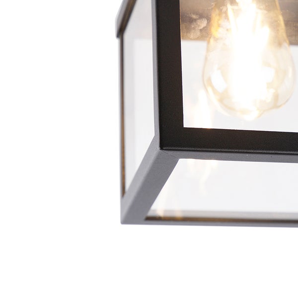 Detailansicht einer modernen Außenlampe mit schwarzem Metallrahmen, Klarglas und eingeschalteter Filament-Glühbirne.