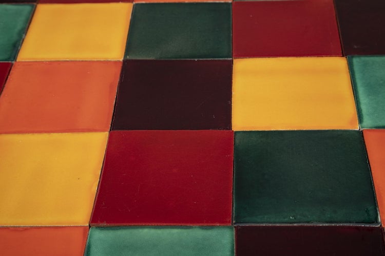Quadratische, verschiedenfarbige Fliesen bilden ein Muster