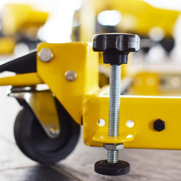 Detailaufnahme eines gelben Werkstattwagens mit Nivellierfuß und Rad