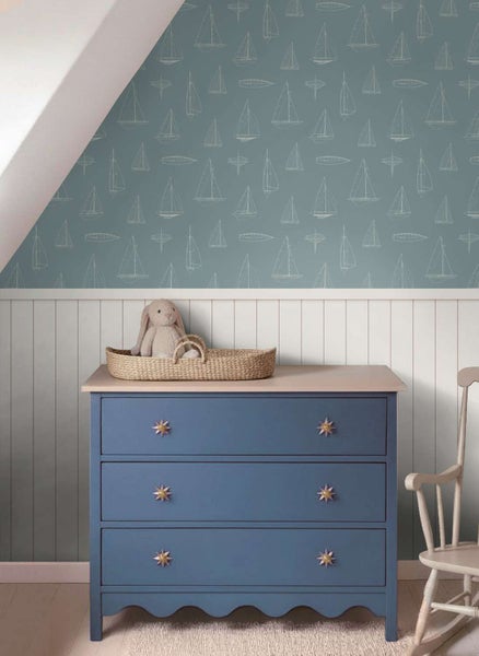 Tapete mit Segelbootmotiv in einem Kinderzimmer mit blauer Kommode und weißer Wandvertäfelung