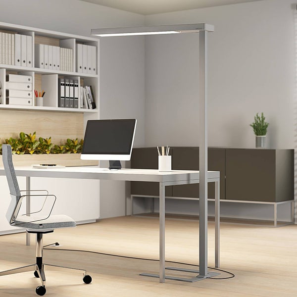 Modernes, helles Büro mit LED-Stehleuchte aus Metall über einem weißen Schreibtisch mit Monitor. Einrichtung mit Regal und Sideboard.