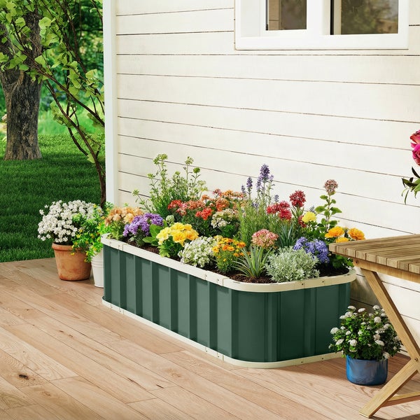 Ein rechteckiges Hochbeet aus Metall in Dunkelgrün mit abgerundeten Ecken, bepflanzt mit bunten Blumen auf einer Holzterrasse.