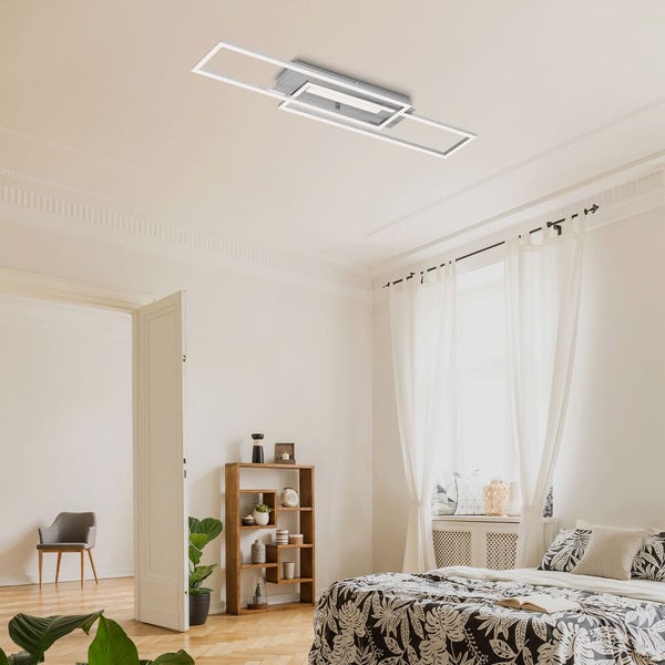 Moderne LED-Deckenleuchte mit drei ineinandergreifenden rechteckigen Rahmen in einem hellen Schlafzimmer mit Parkettboden.