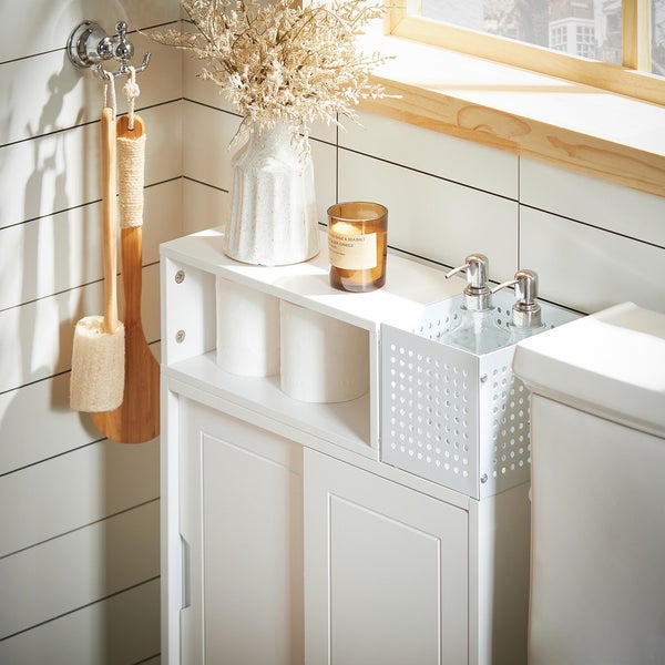 Badezimmer mit Waschtischunterschrank, Seifenspender, Kerze, Toilettenpapier und Bürste