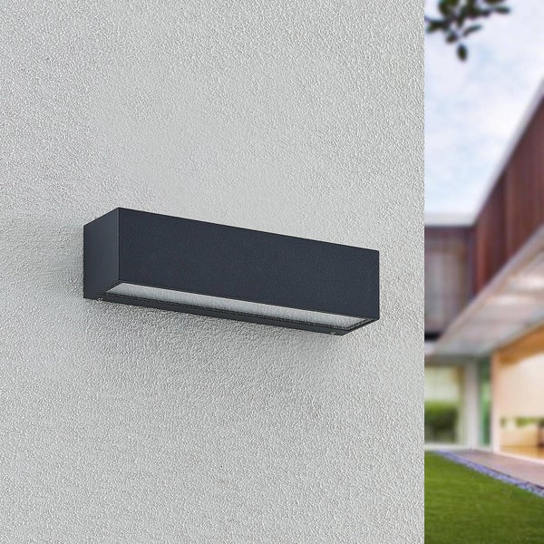 Rechteckige schwarze Außenwandleuchte aus Metall an einer hellen, strukturierten Fassade in einem modernen Außenbereich.