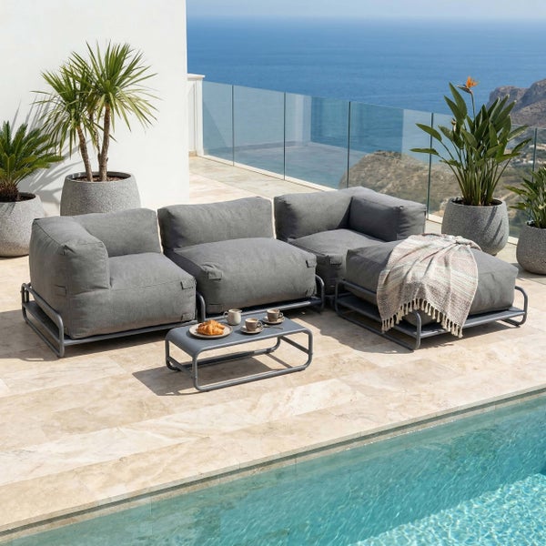 Moderne Garten-Lounge-Gruppe mit grauen Polstern und Metallgestell auf einer hellen Terrasse am Pool mit Meerblick und großen Pflanzenkübeln.