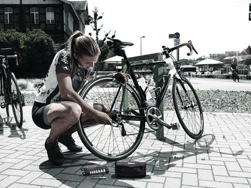 Frau repariert Fahrrad auf der Straße