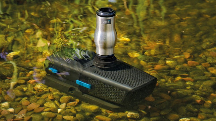 Oase Teichfilter und Wasserspielpumpe im Einsatz unter Wasser auf einem Kiesbett in einem Gartenteich.
