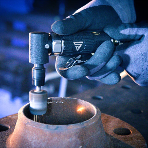 Eine Person benutzt einen Druckluft-Winkelschleifer zum Schleifen eines Metallstücks.