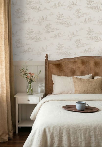 Helles Schlafzimmer mit Toile-de-Jouy-Tapete, Bett mit Kopfteil aus Wiener Geflecht, weißem Nachttisch und beigen Leinenvorhängen.