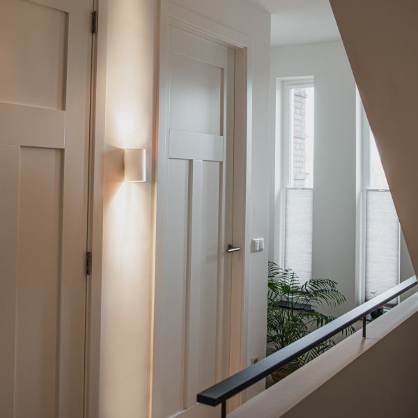 Flur mit Türen, Wandleuchte und Treppengeländer