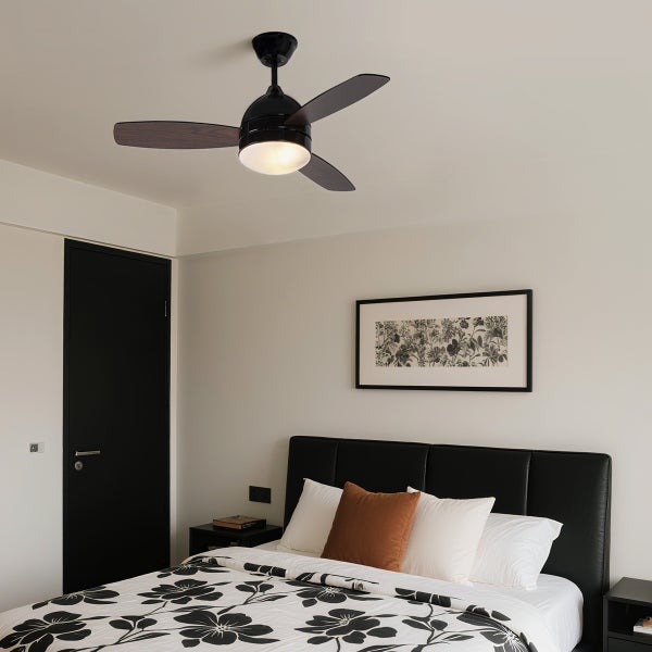 Moderner Deckenventilator mit Beleuchtung installiert in einem stilvoll eingerichteten Schlafzimmer mit schwarzem Bett und floraler Bettwäsche.