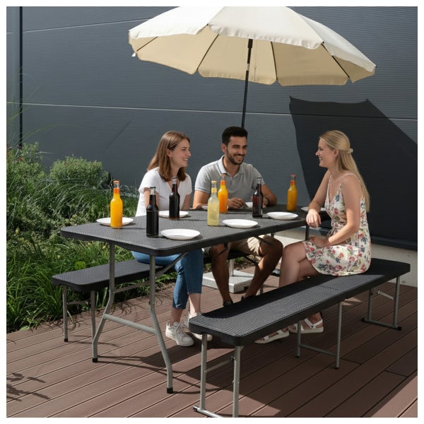 Dreiteilige Klappgarnitur in Rattanoptik bestehend aus einem Tisch und zwei Bänken auf einer Terrasse mit drei Personen unter einem Sonnenschirm.