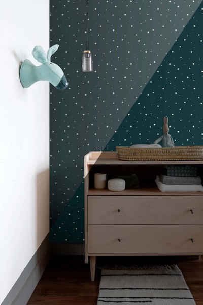 Ein Kinderzimmer mit einer Kommode, einer Stofftier-Trophäe und einer Sternentapete.