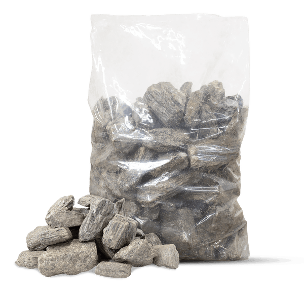 Transparenter Sack mit grauen Natursteinen und einigen losen Steinen davor.