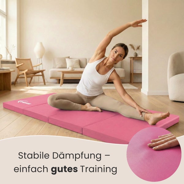 Frau dehnt sich auf einer faltbaren Gymnastikmatte in einem Wohnzimmer.