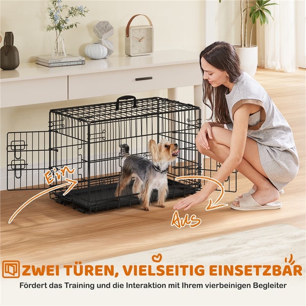 Draht-Hundekäfig mit zwei Türen und einer Frau, die einen kleinen Hund trainiert