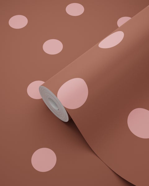 Vliestapete mit großen rosa Punkten auf terrakottafarbenem Hintergrund.