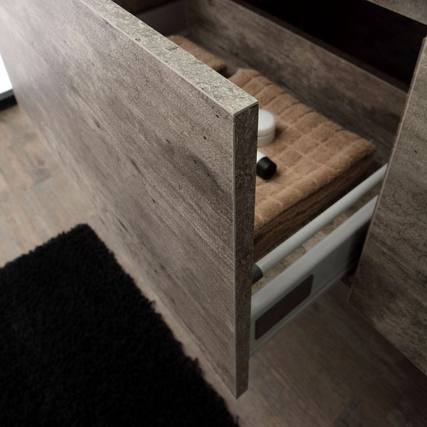 Detailaufnahme eines offenen Waschtischunterschranks mit Handtuch und Pflegeprodukten