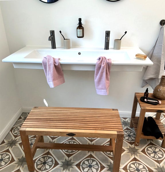 Badezimmer mit Doppelwaschbecken, Holzbänken und gemusterten Bodenfliesen für eine helle und organisierte Atmosphäre