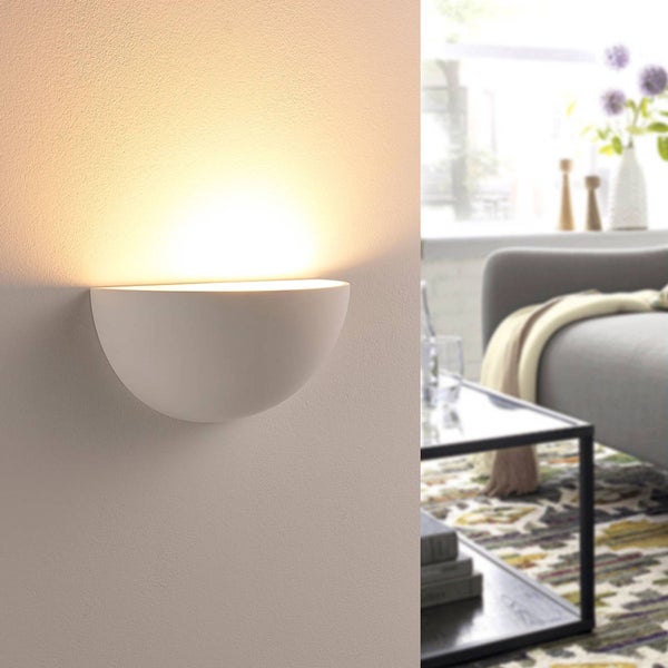 Halbrunde Wandleuchte aus Gips in einem hellen, modern eingerichteten Wohnzimmer mit Sofa und Couchtisch, montiert an der Wand mit Lichtschein nach oben.