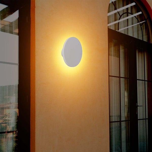Eine runde Wandleuchte strahlt helles Licht an einer Wand aus.