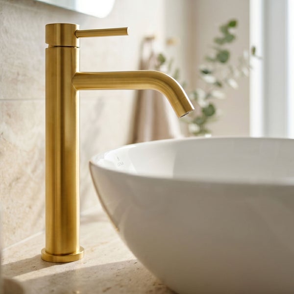 Hohe Einhebel-Waschtischarmatur in Gold-Optik matt, neben einem weißen Aufsatzwaschbecken in einem hellen Badezimmer.